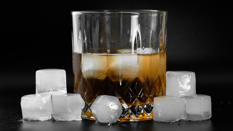 Whiskey shown in a glass tumbler with ice, surrounded by ice cubes