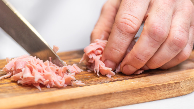 Chopping ham on wooden cutting board