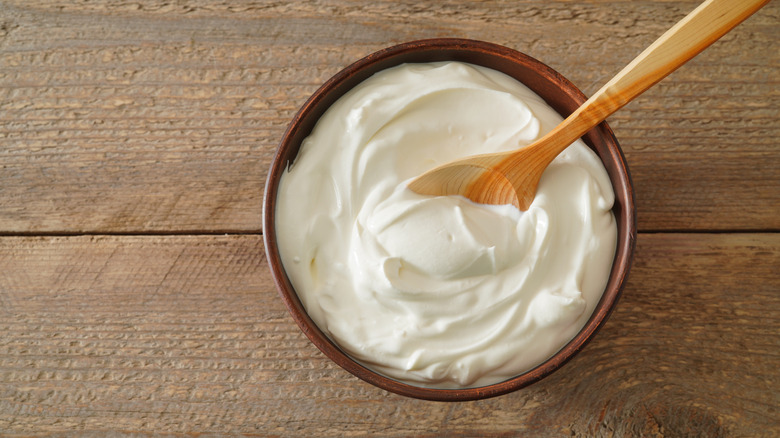 Bowl of sour cream with wooden spoon