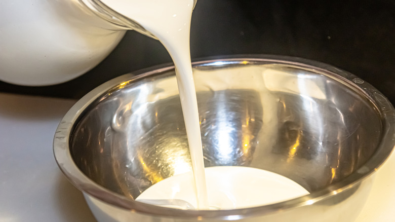 Pouring heavy cream from jug into mixing bowl