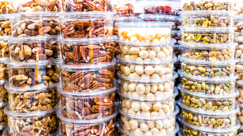 plastic round containers of walnuts, macademia, and pistachios for sale