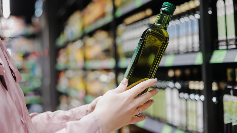 woman chooses glass jar of olive oil at store