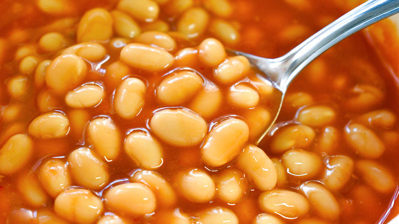 Close up of spoon digging into bowl of baked beans