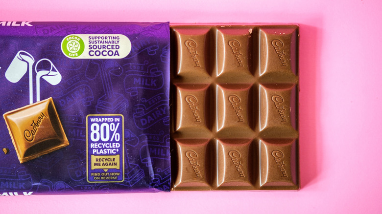 Opened bar of Cadbury chocolate on pink background