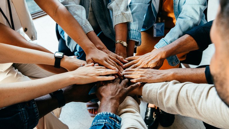 people putting hands in a circle