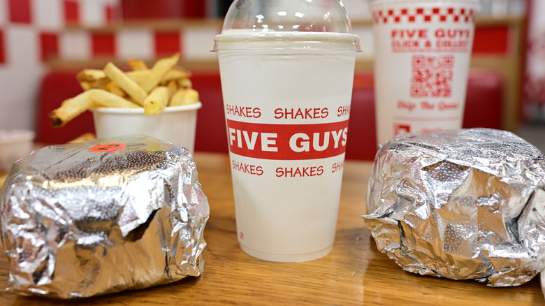Drinks burgers and fries from Five Guys on restaurant table