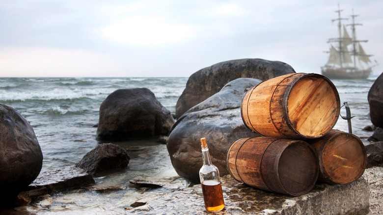 A pirate backdrop with rum and barrels on the beach, and a pirate ship behind.