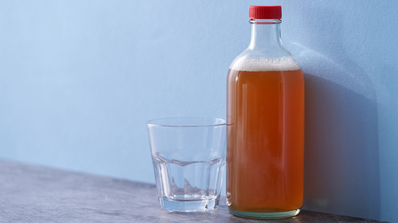 bottle of apple cider vinegar and empty drinking glass.