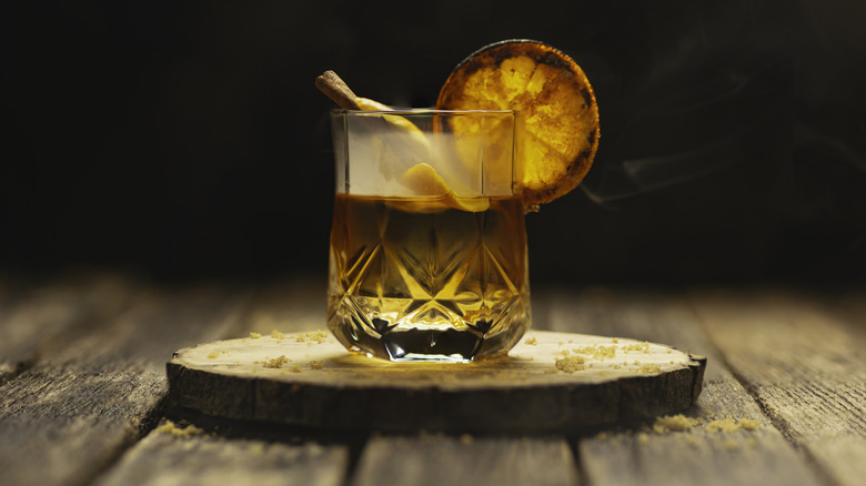 An old-fashioned cocktail garnished with a dehydrated orange slice