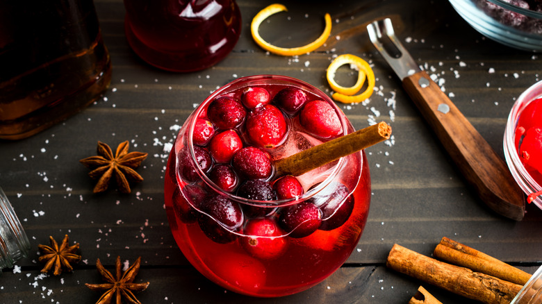A festive fall drink with cranberries, cinnamon, and orange curls