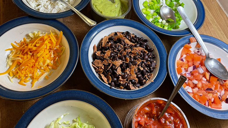 Various burrito bowl toppings in bowls for self-serving