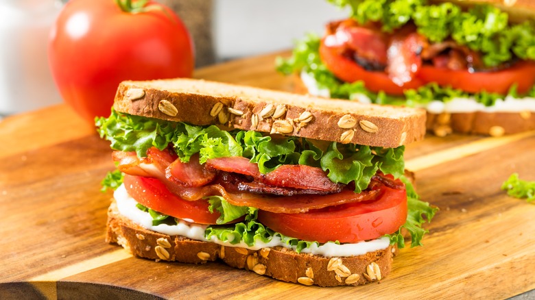 Two BLT sandwiches on wooden cutting board