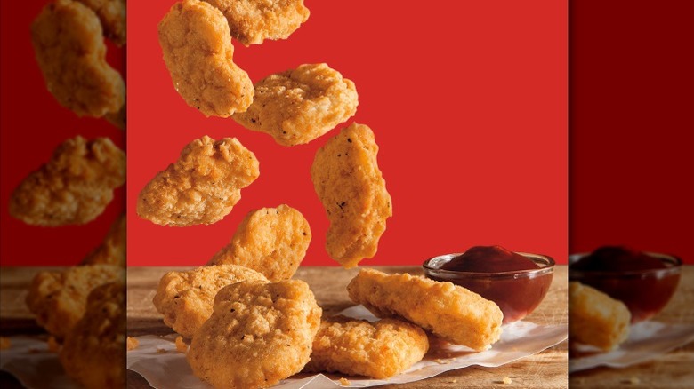 Burger King chicken nuggets falling onto a table with a side of BBQ sauce..