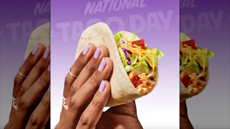 Hand holding Taco Bell taco for National Taco Day.
