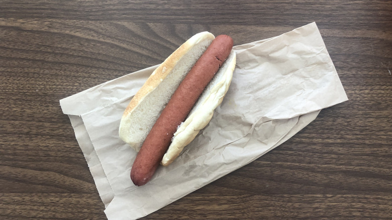 Costco plain hot dog on paper bag on wooden table.