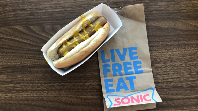 Sonic All-American hot dog with mustard in paper box with paper to-go bag.