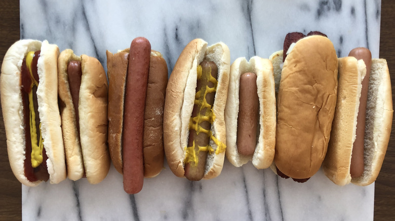 Line of seven hot dogs from different fast food restaurants.