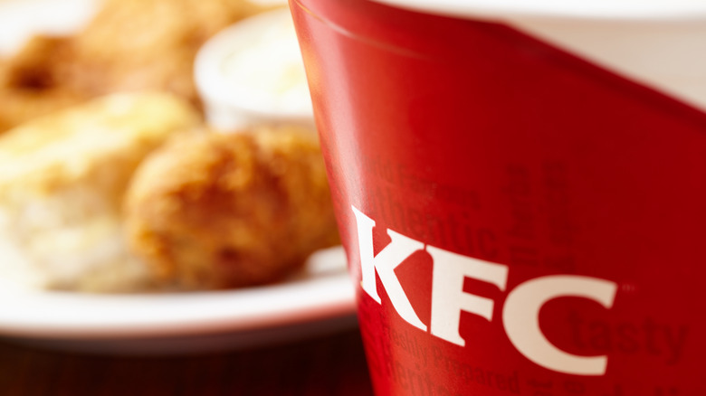 Red bucket with KFC logo and chicken blurred in background