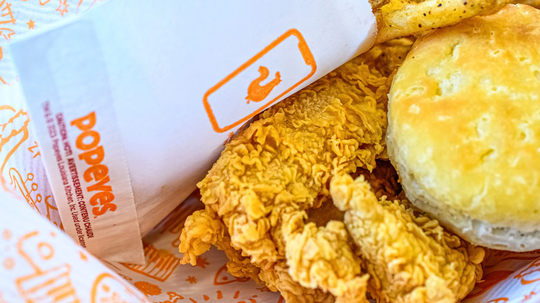 Closeup of Popeyes chicken, biscuit, and fries on paper