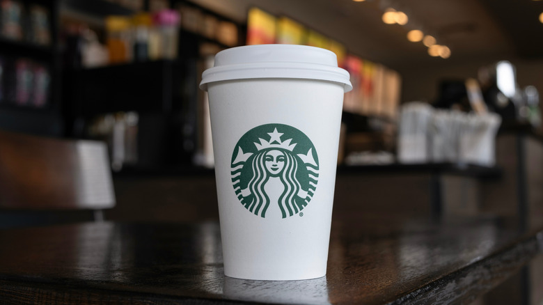 Classic paper cup of Starbucks coffee on table in store