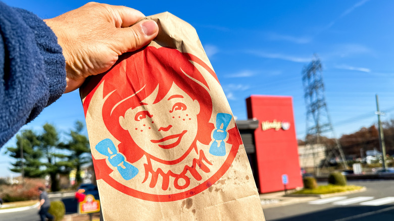 Hand holding a Wendy's bag outside in front of restaurant