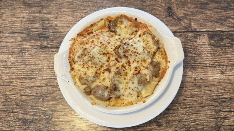 Top view of Fazoli's spicy baked ziti with Italian sausage in a white dish served on a wooden table