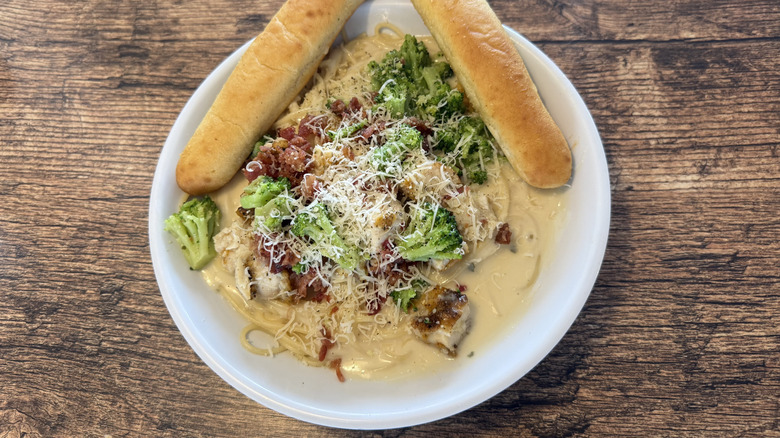 Top view of Fazoli's Chicken Carbonara with breadsticks served on wood table