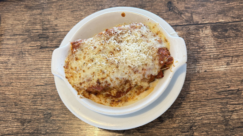 Fazoli's baked lasagna inside a round dish topped with cheese and served on a wooden table