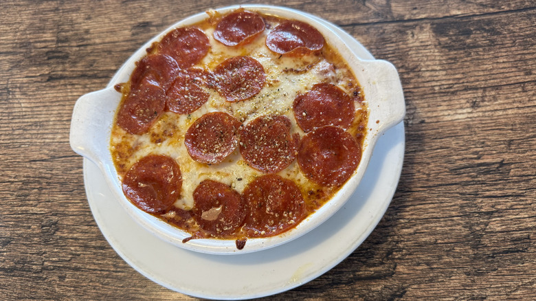Fazoli's pizza baked spaghetti inside a round white plate served on a wooden table