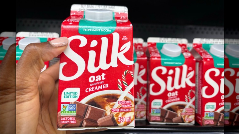 Person holding a small carton of Silk peppermint mocha oat creamer