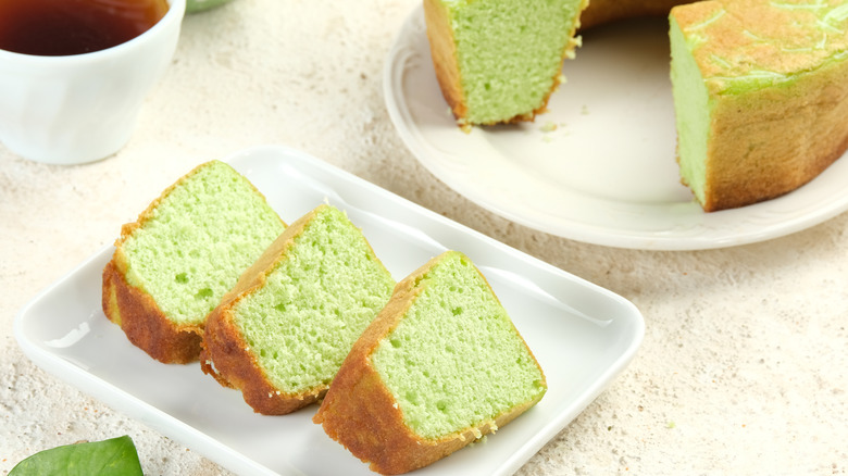 Green colored pandan sponge cake on a plate with tea