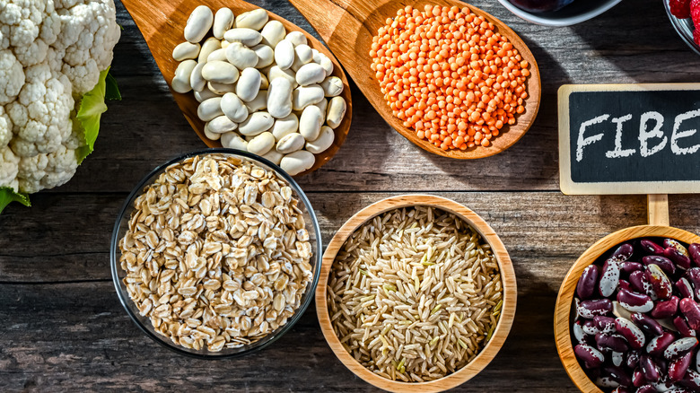 A sign that says "fiber" surrounded by fibrous fruits, veggies, legumes, seeds, and nuts