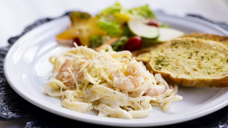 Plate with pasta, garlic toast, and salad in small portions