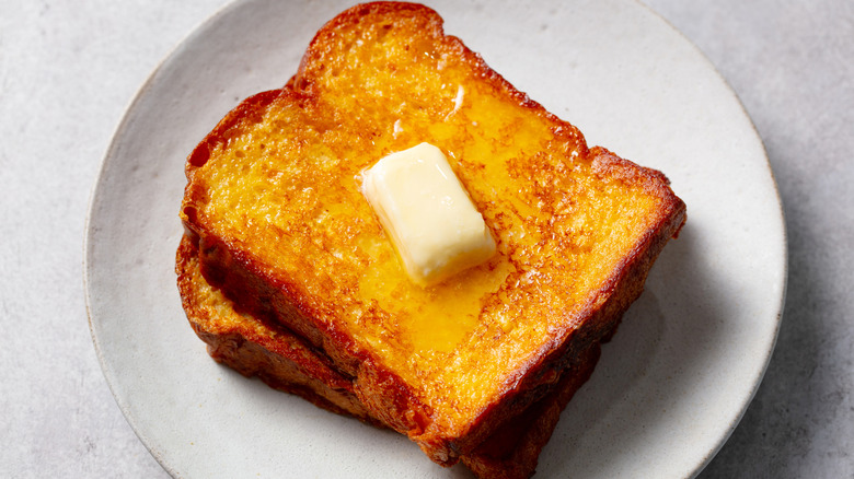 French toast slices with melting butter on white plate