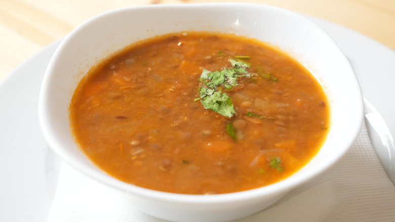 Closeup of lentil soup in white bowl on white plate