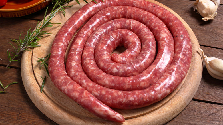 Pork luganega sausage on a round wooden cutting board