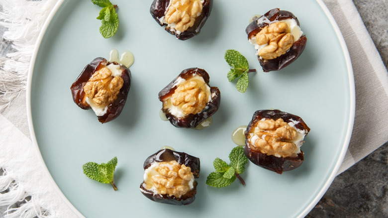 Stuffed dates with cream cheese, walnuts, and honey close-up on a blue plate