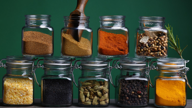 A selection of Herbs and Spices in jars in front of green background