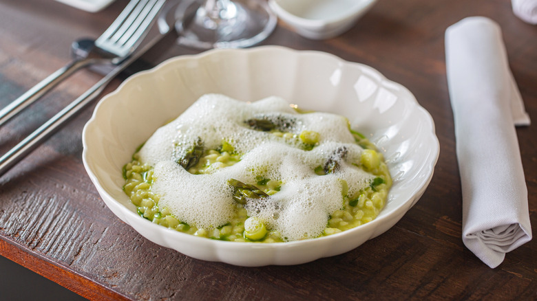 Bowl of green risotto topped with foam