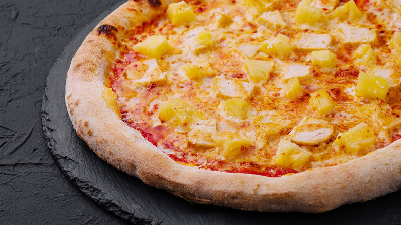 Pizza with pineapple on dark grey platter