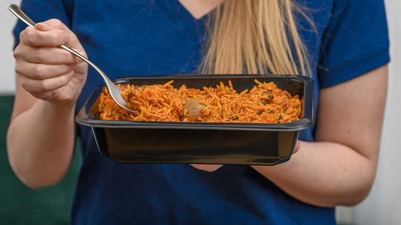 Person eating rice-based ready meal from plastic container