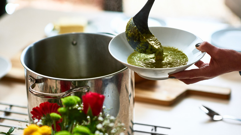Ladeling green soup from pot into bowl
