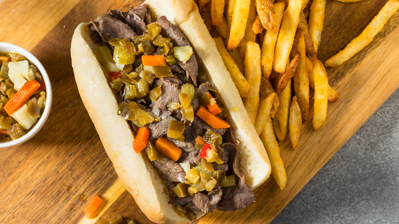 Italian beef sandwich with fries on wooden cutting board