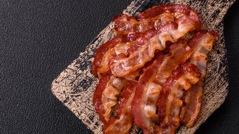 fried bacon with salt and spices on a dark background
