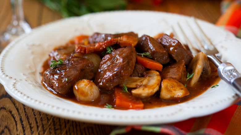 Beef bourguignon in white dish on table.