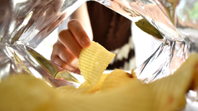 Woman's hand reaching into bag of chips