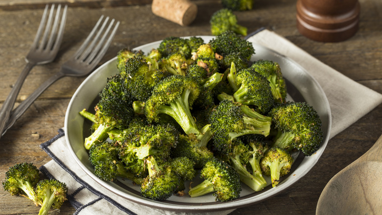 Roasted broccoli on plate with two forks and napkin