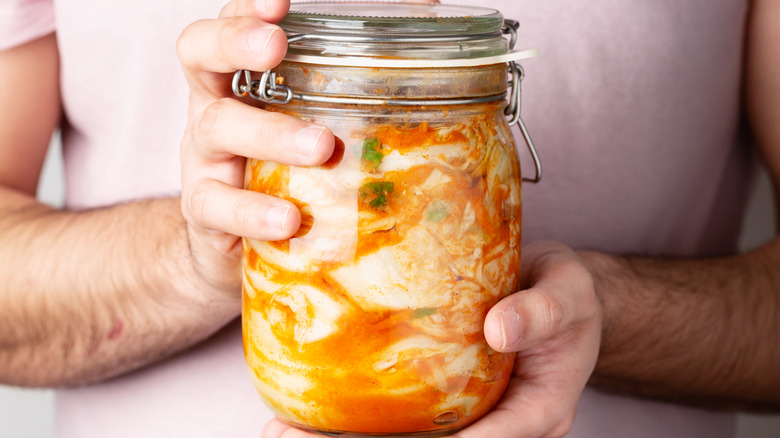 Man holding jar of homemade kimchi