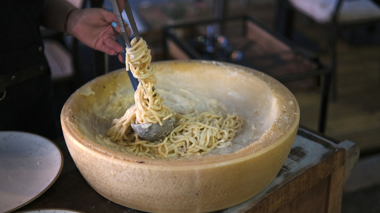 Twirling creamy spaghetti in a wheel of parmesan
