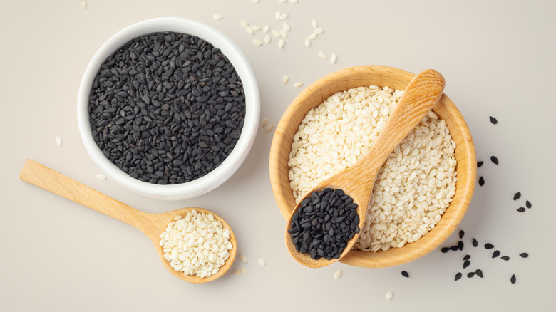 Bowls and spoons of white and black sesame seeds